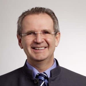 A man in glasses and a tie smiling